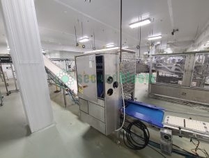 Roopack branded filling equipment with stainless steel perforated panels and conveyor system in food processing facility