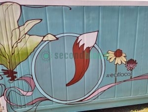 Close-up of container farm mural showing large green aquatic plants with red roots, pink water swirls, and flowers with #eatlocal hashtag on blue background